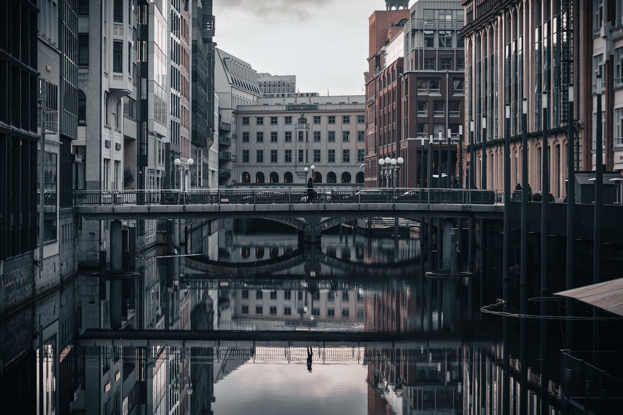 Urban scene capturing modern architecture reflecting on a calm canal in Hamburg, Germany.